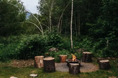 a fire pit in the middle of a yard with trees at Le Fitzsimmons in Mansonville