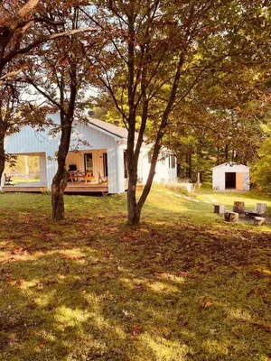 a white house with two trees in a field at Le Fitzsimmons in Mansonville