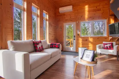 a living room with a couch and a table at Vacances Magiques Chalet Skadi Paix Nature in Saint-Justin