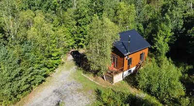 an orange house in the middle of a forest at Vacances Magiques Chalet Skadi Paix Nature in Saint-Justin