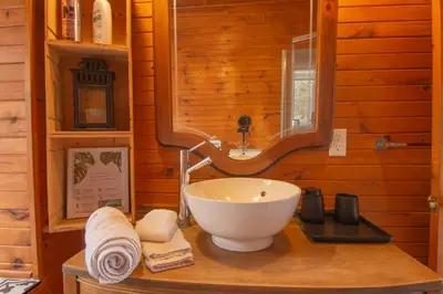 a bathroom with a bowl sink and a mirror at Vacances Magiques Chalet Skadi Paix Nature in Saint-Justin
