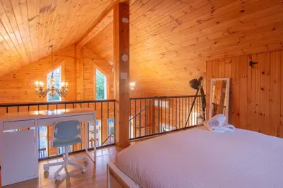 a bedroom with a bed and a desk on a balcony at Vacances Magiques Chalet Skadi Paix Nature in Saint-Justin