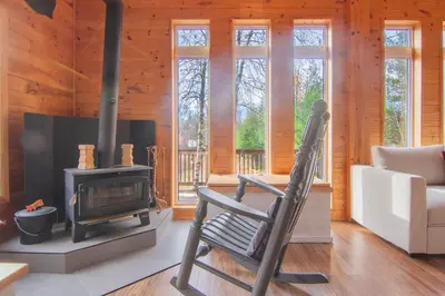 a rocking chair in a living room with a stove at Vacances Magiques Chalet Skadi Paix Nature in Saint-Justin