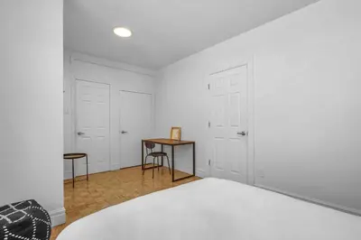 a white bedroom with a bed and a table at Sophisticated Two Bedroom Hideaway in Westmount in Montréal
