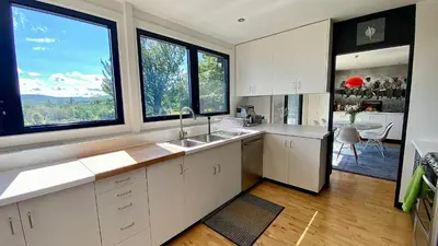 a kitchen with white cabinets and two large windows at Le domaine Primavesi in West Brome