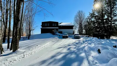 two cars parked on a snow covered road in front of a house at Le domaine Primavesi in West Brome