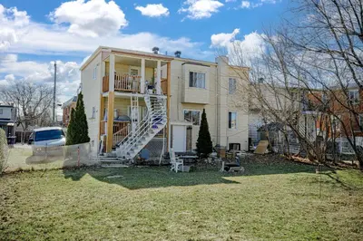 a house with a spiral staircase in front of it at Charmant appartement de 2 pièces et proche du Métro in Laval