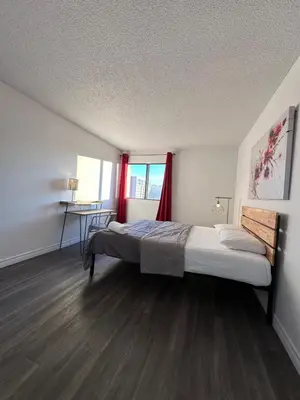 a bedroom with a bed and a window with red curtains at The FIVE in Montréal