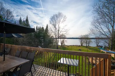 a balcony with a table and chairs and a view of a lake at Chalet des Oiseaux Bleus, Spa, Lac in Saint-Gérard