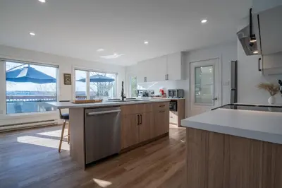 a large kitchen with wooden floors and white cabinets at Chalet des Oiseaux Bleus, Spa, Lac in Saint-Gérard