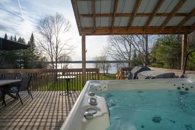 a hot tub on a patio with a table and chairs at Chalet des Oiseaux Bleus, Spa, Lac in Saint-Gérard