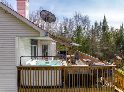a deck with a hot tub on a house at Chalet des Oiseaux Bleus, Spa, Lac in Saint-Gérard