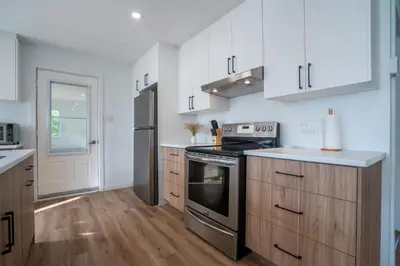 a kitchen with white cabinets and a stove at Chalet des Oiseaux Bleus, Spa, Lac in Saint-Gérard