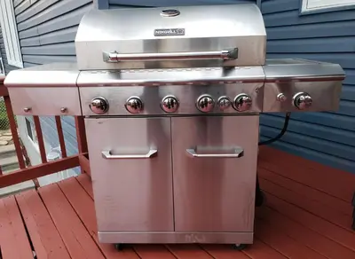a grill sitting on a deck next to a house at La campagne en ville avec spa in Laval
