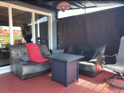 a porch with two leather couches and a table at La campagne en ville avec spa in Laval