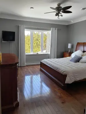 a bedroom with a bed and a ceiling fan at La campagne en ville avec spa in Laval