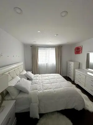 a bedroom with a large white bed and a window at Luxury bungalow in Châteauguay