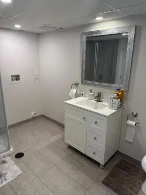 a bathroom with a white sink and a mirror at Luxury bungalow in Châteauguay