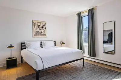 a white bedroom with a bed and a large window at The Slant - Trendy Spot in the Heart of Montreal in Montréal