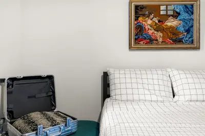 an open suitcase sitting next to a bed with a painting at The Slant - Trendy Spot in the Heart of Montreal in Montréal