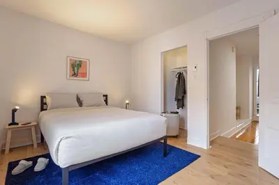 a bedroom with a large white bed and a blue rug at The Slant - Trendy Spot in the Heart of Montreal in Montréal