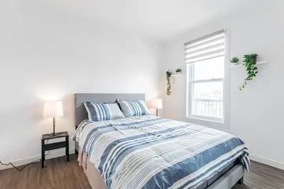 a white bedroom with a bed and a window at Modern 3 bedroom condo in Montréal