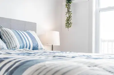 a bed with blue and white sheets and a lamp at Modern 3 bedroom condo in Montréal