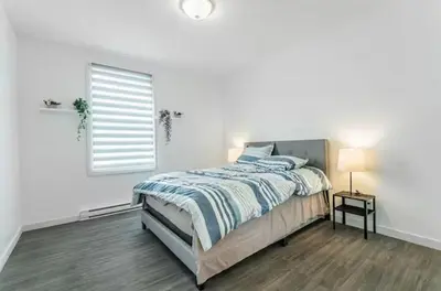 a white bedroom with a bed and a window at Modern 3 bedroom condo in Montréal