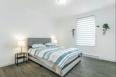 a white bedroom with a bed and a window at Modern 3 bedroom condo in Montréal