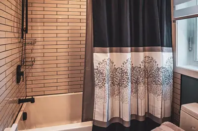 a shower curtain with trees on it in a bathroom at Le Pignon Vert in Sainte-Séraphine