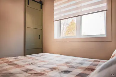 a bedroom with a bed and a window with a window blind at Le Pignon Vert in Sainte-Séraphine