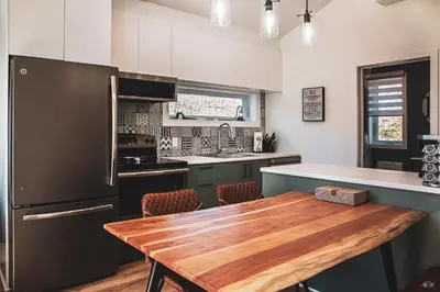 a kitchen with a wooden table and a black refrigerator at Le Pignon Vert in Sainte-Séraphine