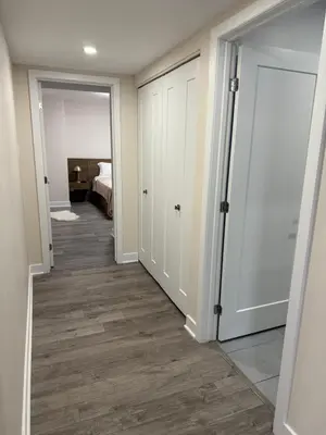 a hallway with white doors and wood floors at Confort & Harmonie in Longueuil