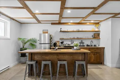 a kitchen with a large wooden island with bar stools at Le nid des hirondelles in Windsor