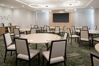 a conference room with tables and chairs and a projection screen at Hyatt Place Montreal Airport in Dorval