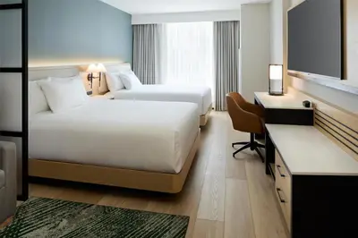 a hotel room with two beds and a desk at Hyatt Place Montreal Airport in Dorval