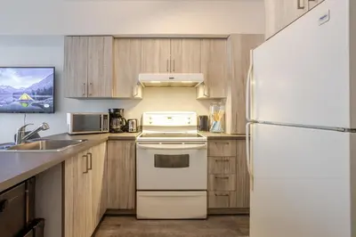 a kitchen with a white refrigerator and wooden cabinets at Stylish 3BR in Griffintown in Montréal