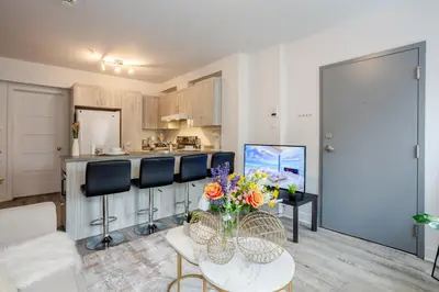 a living room with a table and chairs and a kitchen at Fashionable 3BR in Griffintown in Montréal