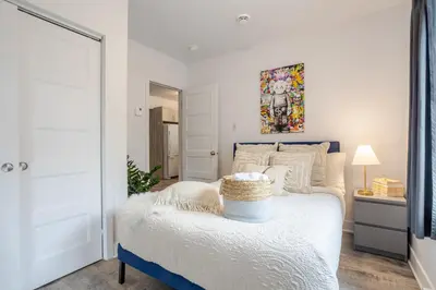 a white bedroom with a bed with a blue frame at Fashionable 3BR in Griffintown in Montréal