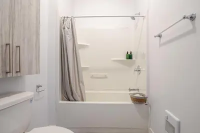 a white bathroom with a shower and a toilet at Chic and Spacious 3 Bedrooms in Griffintown in Montréal