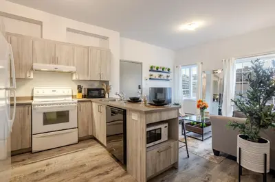 a kitchen with white appliances and wooden cabinets at Chic and Spacious 3 Bedrooms in Griffintown in Montréal