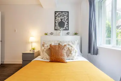 a bedroom with a bed with a yellow blanket and a window at Cozy and Spacious Condo Downtown in Montréal