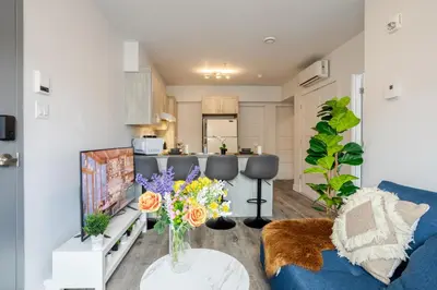a living room with a blue couch and a kitchen at Modern 3BR in Griffintown in Montréal