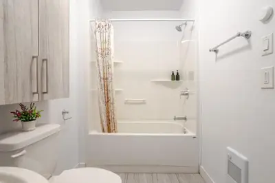 a white bathroom with a tub and a toilet at Modern 3BR in Griffintown in Montréal