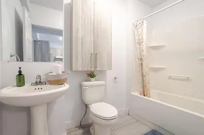 a white bathroom with a toilet and a sink at Modern 3BR in Griffintown in Montréal