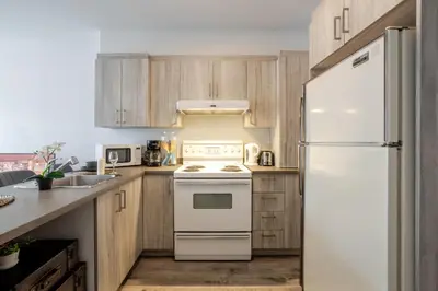 a kitchen with a white refrigerator and wooden cabinets at Modern 3BR in Griffintown in Montréal