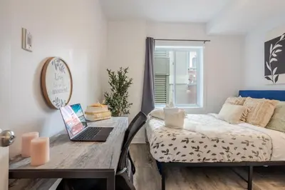 a bedroom with a bed and a desk with a laptop at Modern 3BR in Griffintown in Montréal