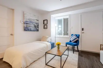 a bedroom with a bed and a blue chair at Amazing 4 Bedroom Unit in Downtown in Montréal