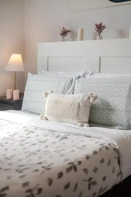a white bed with a teddy bear sitting on it at Modern Apartment in the Heart of Griffintown in Montréal
