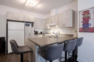 a kitchen with a sink and a counter with chairs at Wonderful 4 BR Home in the heart of Downtown in Montréal